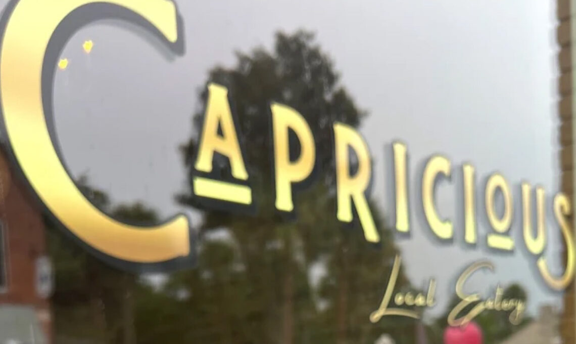Front window of Capricious restaurant with gold lettering spelling out the name